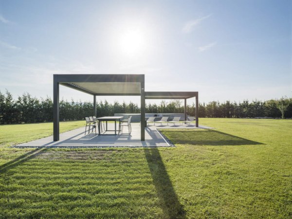 Das freistehende Lamellendach Varia von Gibus auf einer großen Grünfläche mit einem Sonnenbereich und einen Essbereich.