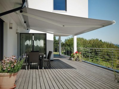 Die schlichte und ovale Markise Cleo 7040 von Hella, auf einer Terrasse mit Zugang zum Garten.