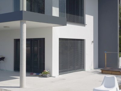 Familienhaus mit Raffstoren und eine Terrasse mit Pool.