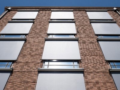 Die Senkrechtmarkise für Fenster als Sonnenschutz an einem Backsteinhaus.
