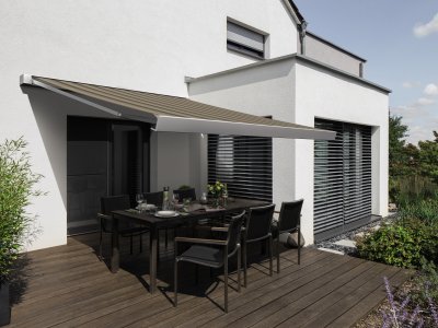 Die Kassettenmarkise K50 von Warema auf einer Terrasse an einem Einfamilienhaus mit Garten.