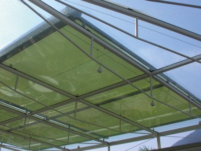 Hella Wintergartenmarkise Tenda mit hellgrünen Markisentuch und überhalb einem großen Glasdach.