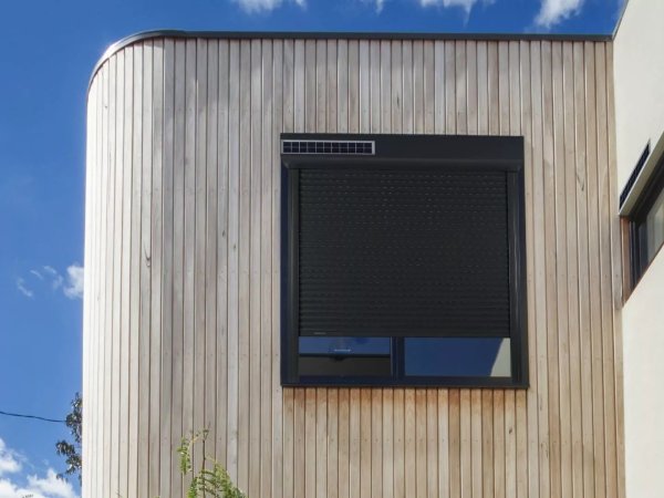 Der autarke Solar Rollladen von Bubendorff an einem modernen Wohnhaus mit Holzfassade.