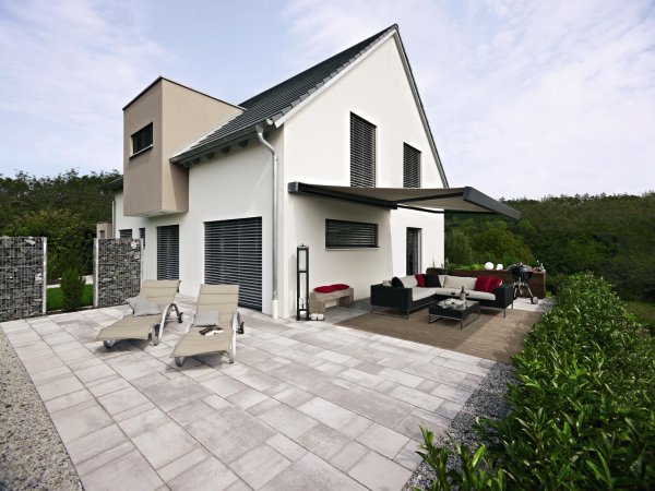Die Warema K70 Kassettenmarkise an einem EInfamilienhaus mit großer Terrasse mit Garten.