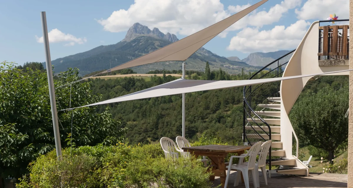 Das verstellbare dreieckige Sonnensegel Ingenua von Umbrosa auf einer Terrasse mit zwei montierten Segel, bei Frimey GmbH.