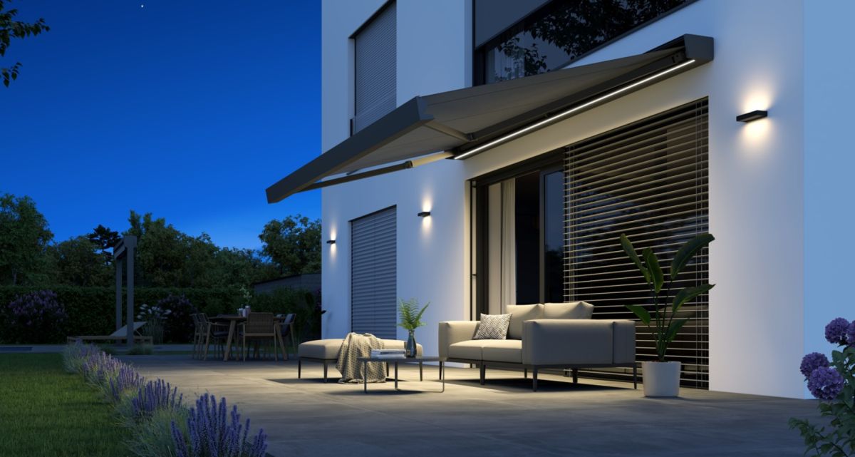 Die eckige Kassettenmarkise Artbox von WOundWO mit LED-Beleuchtung auf einer abendlichen Terrasse mit halb ausgefahrenem Tuch, bei Frimey GmbH.