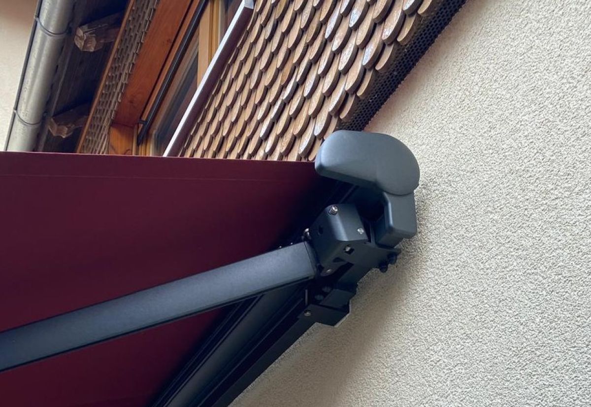 Die hochwertige Halbkassettenmarkise York von Freund Sunshade an der Hauswand mit Bordeaux farbenen Tuch, von Frimey GmbH.