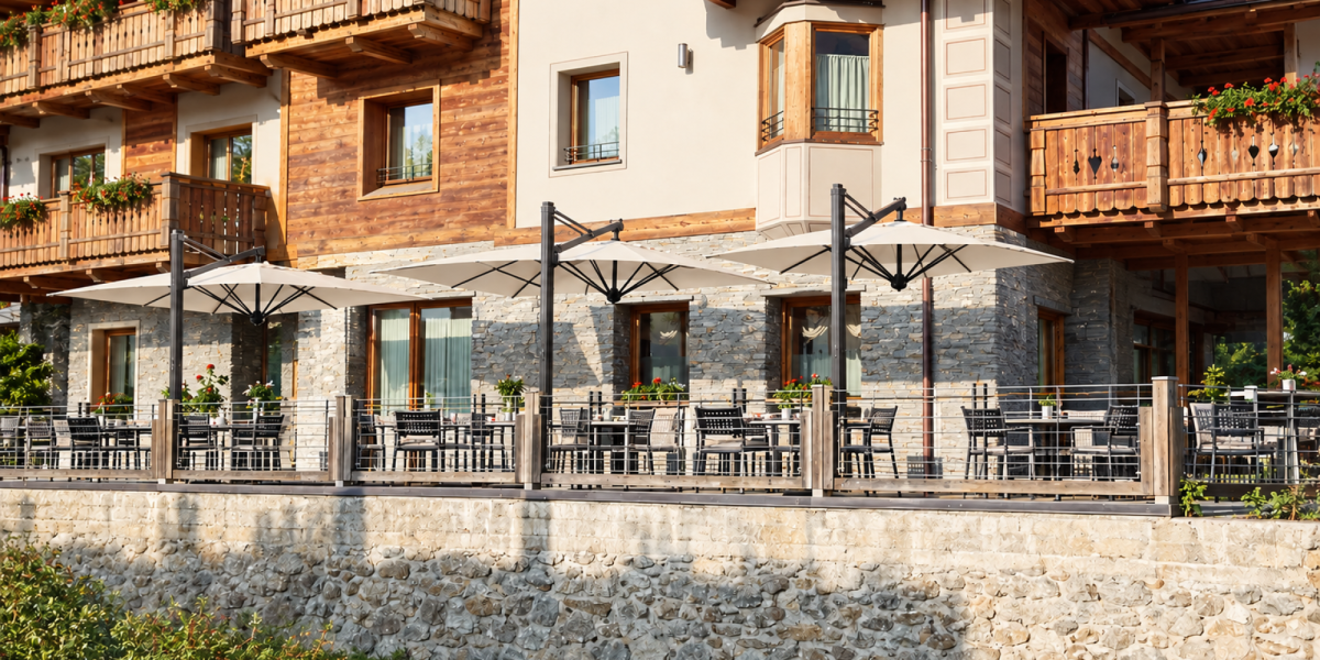 Der hochwertige Ampelschirm Scolaro auf der Terrasse eines Berg-Chalet, als Sonnenschutz und Wetterschutz, bei Frimey GmbH.