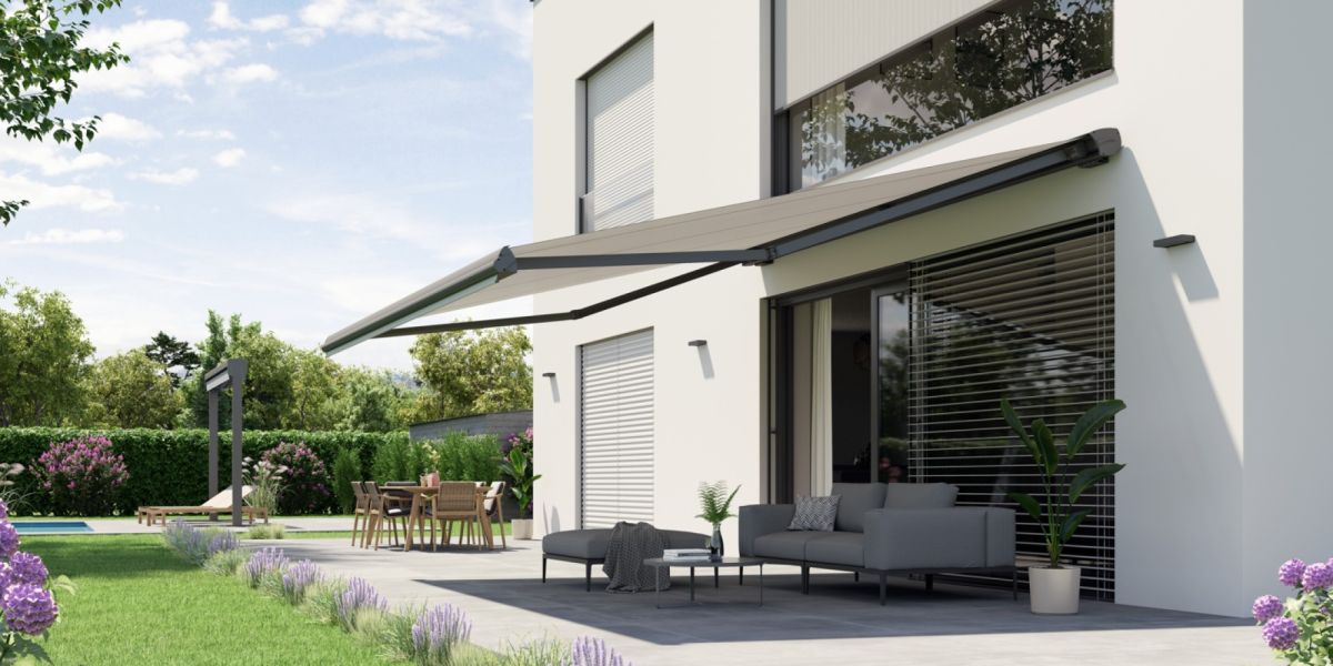 Die hochwertige Halbkassettenmarkise Topline Plus von WOundWO an einer Hauswand mit Terrasse und idylischen Garten, bei Frimey GmbH.