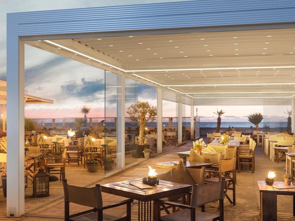 Die Gastronomie Pergola Gibus Azimut auf einer Restaurant Terrasse mit Tische unter der regensicheren Überdachung.