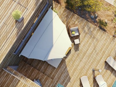 Das C4Sun Elips Sonnensegel auf einer Terrasse mit Holzfußboden und Sonnenliegen.
